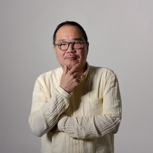 第3研究室 教授 松下計 プロフィール写真2 / 顎に手を当て、考え込むポーズ。真面目な顔で正面を向いている。