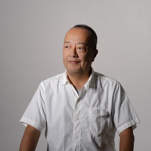 第6研究室　教授　長濱雅彦 プロフィール写真1 / 体は正面を向き、斜めを見つめている。朗らかな表情。