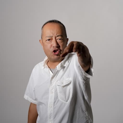 第6研究室　教授　長濱雅彦 プロフィール写真2 / 正面を向き、カメラを指差すポーズを取っている。