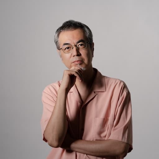 第8研究室　教授　押元一敏 プロフィール写真2 / 顎に手を当て、真面目な表情で正面を向いている。