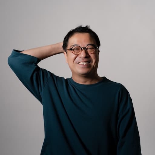 第3研究室　教授　鈴木太朗 プロフィール写真2 / 体ごと正面を向いていて、頭を掻きながら破顔している。